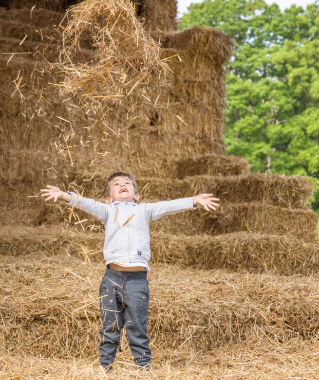 enfant qui jette de la paille au dessus de lui