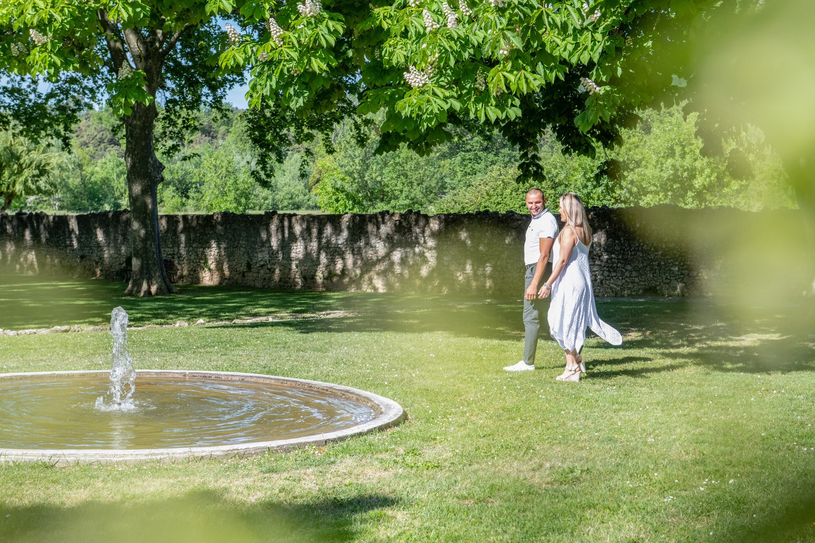 couple se promène dans le jardin à coté d'une fontaine