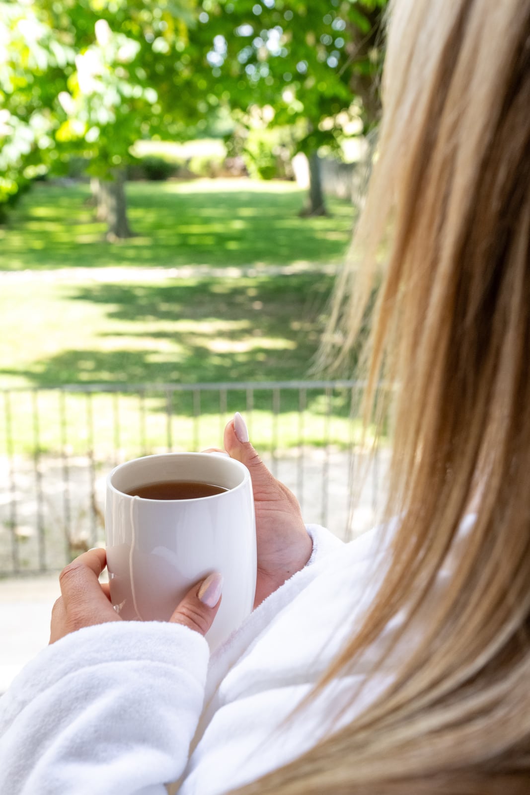 tasse de thé dans les mains face au jardin