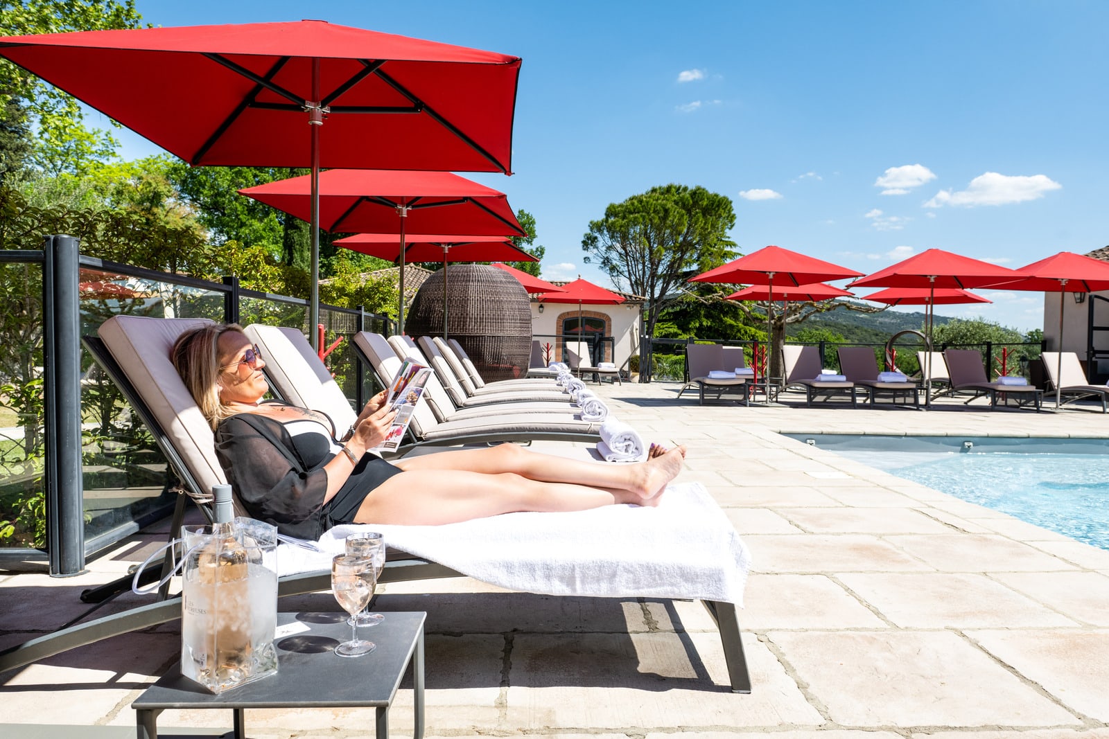 femme lit sur un transat face à la piscine