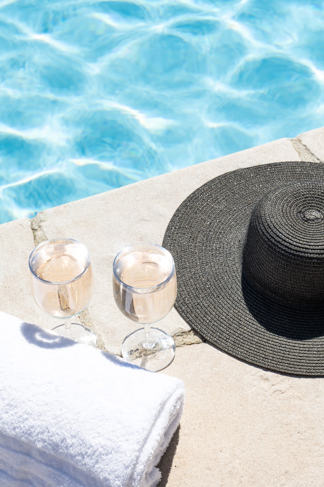 verres de vin et chapeau en bord de piscine