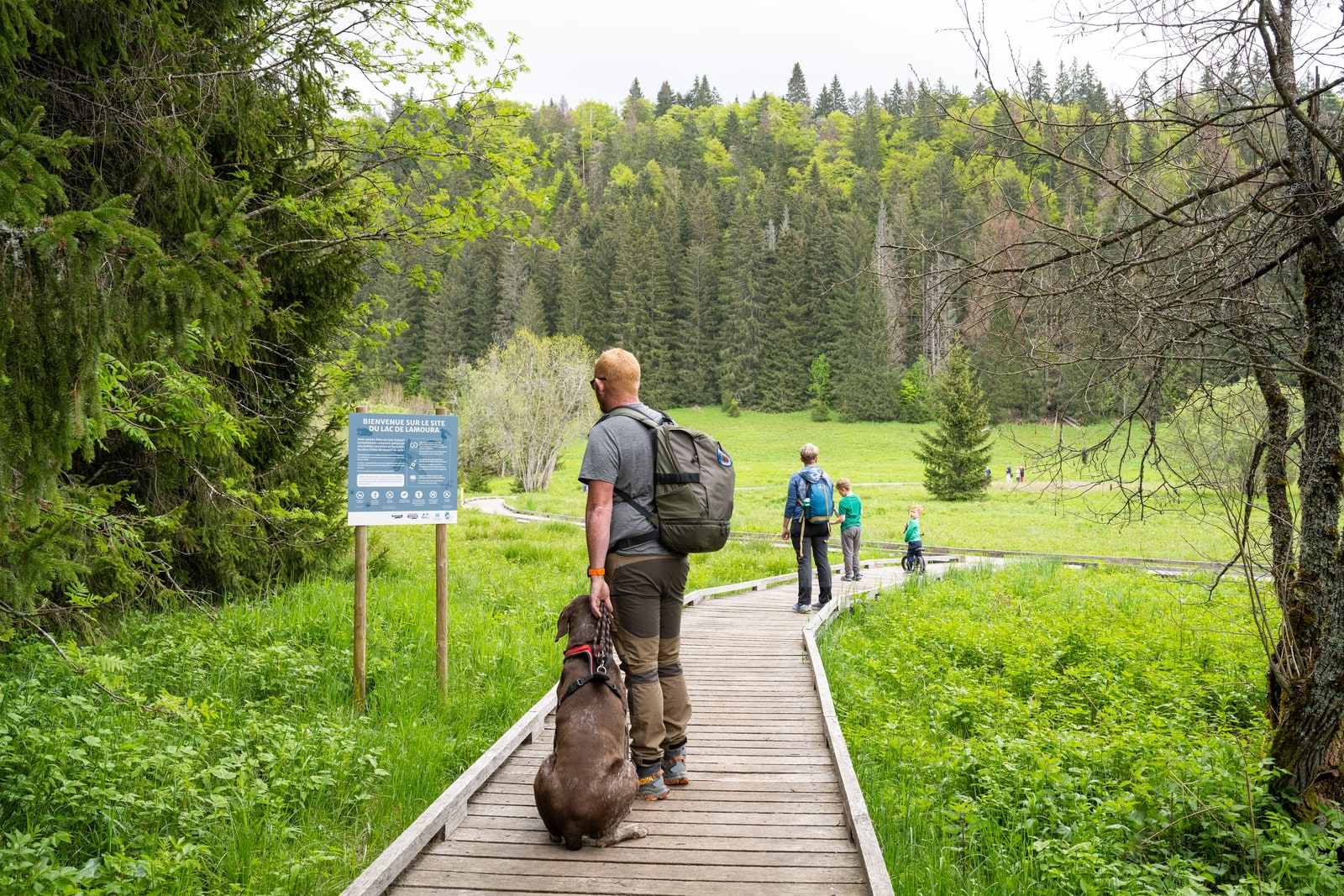 randonneurs et chien devant panneau d'information