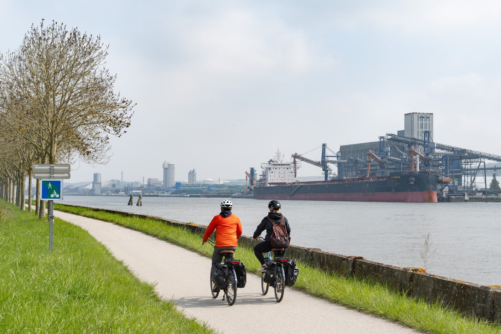 cyclistes sur voie verte le long d'une zone industrielle