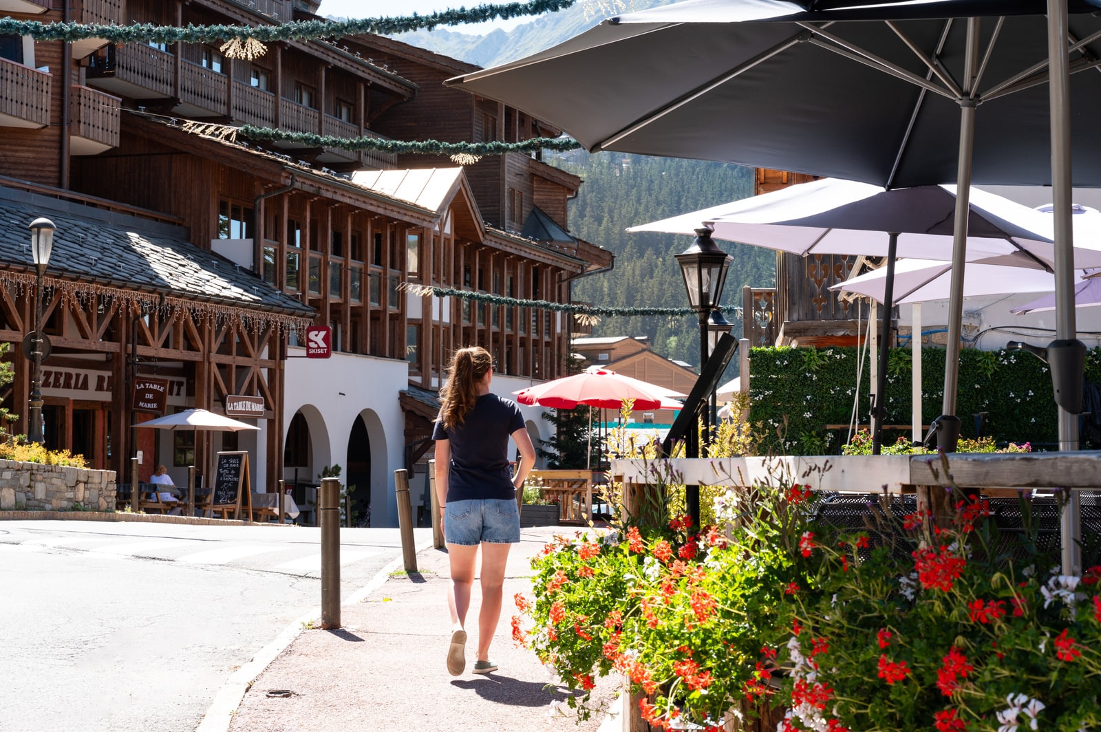 femme marche dans une ruelle de la station de ski en été